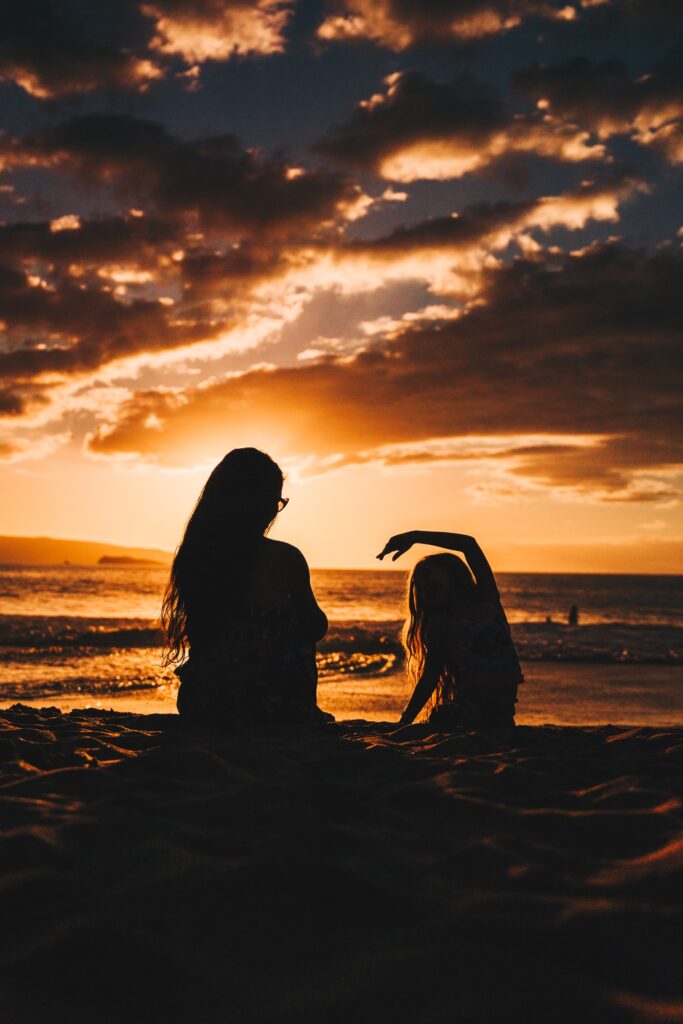 Mother and child enjoy a beach at sunset.