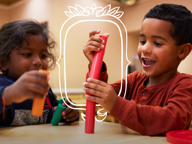 Two smiling children playing with toys at the Crème de la Crème private kindergarten.