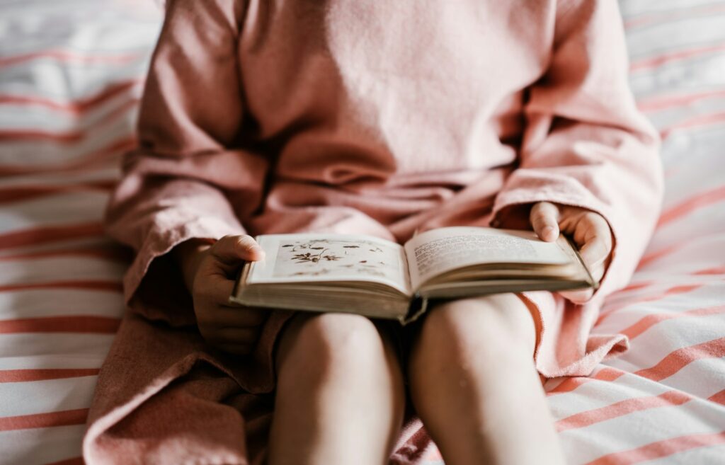 A young child reading a language book in bed in Ellisville, MO