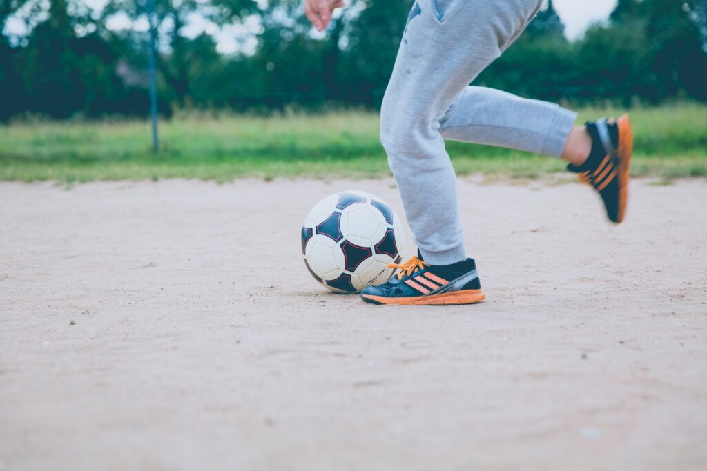 A child kicking a soccer ball during summer camp.
