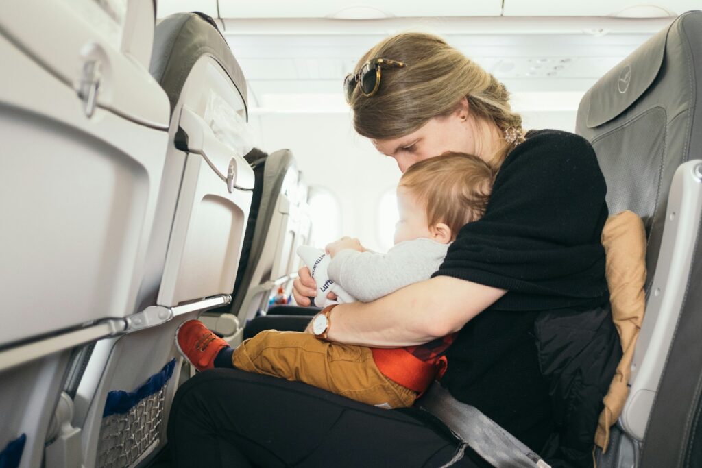 A woman holding a small baby on an airplane.