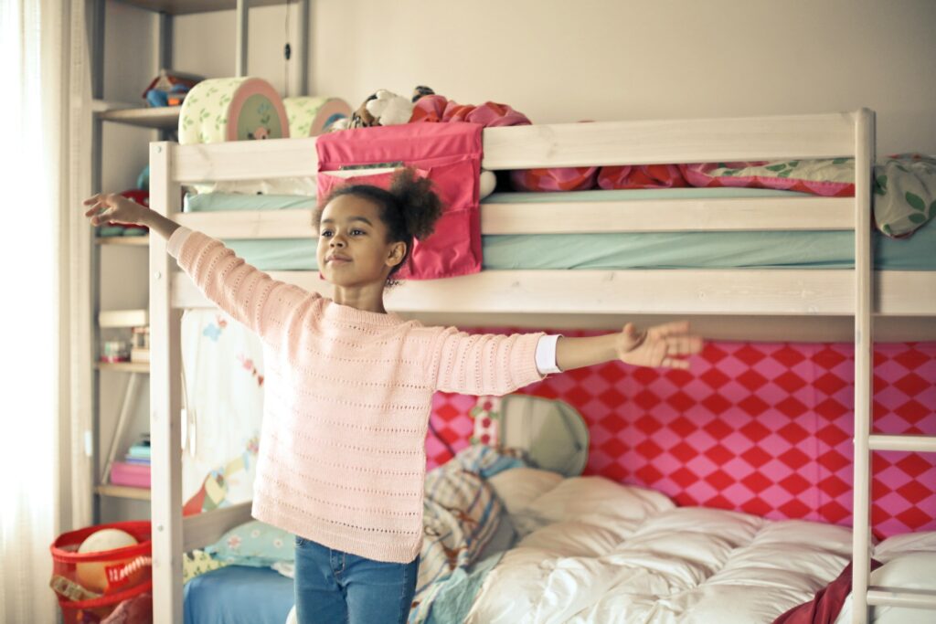 A child stretching out next to a bunk bed.