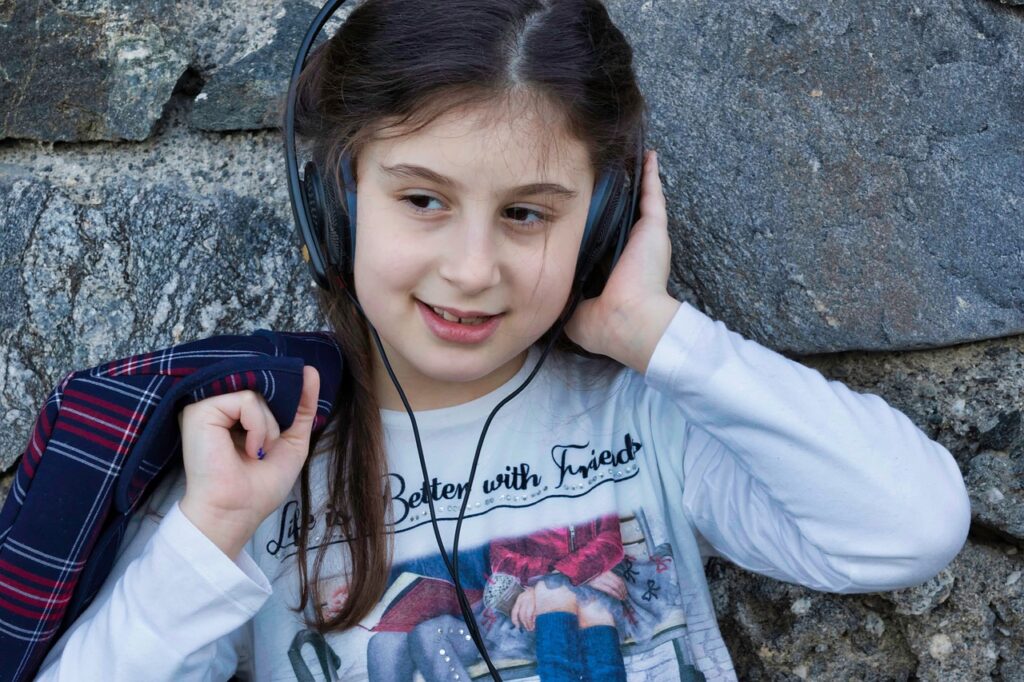A child listening to new kids' music on headphones.