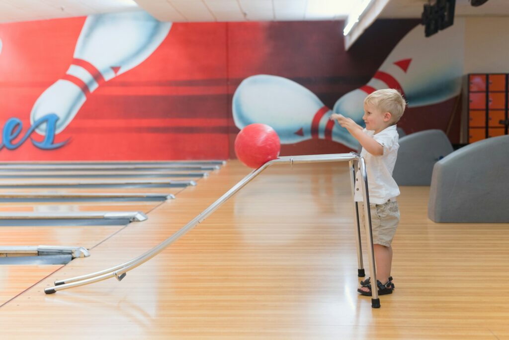 A child rolling a bowling ball down a slide onto an alley at a lane in Peoria, AZ