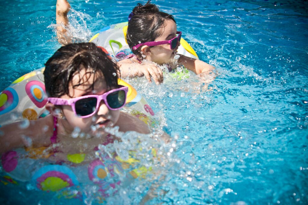 2 kids swimming in a pool with floaties