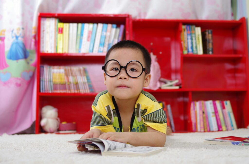 Boy reading a book in front of a bookcase