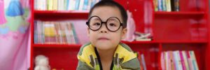 Boy reading a book in front of a bookcase