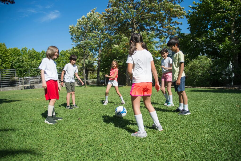 Children outdoors on the soccer field kicking the ball