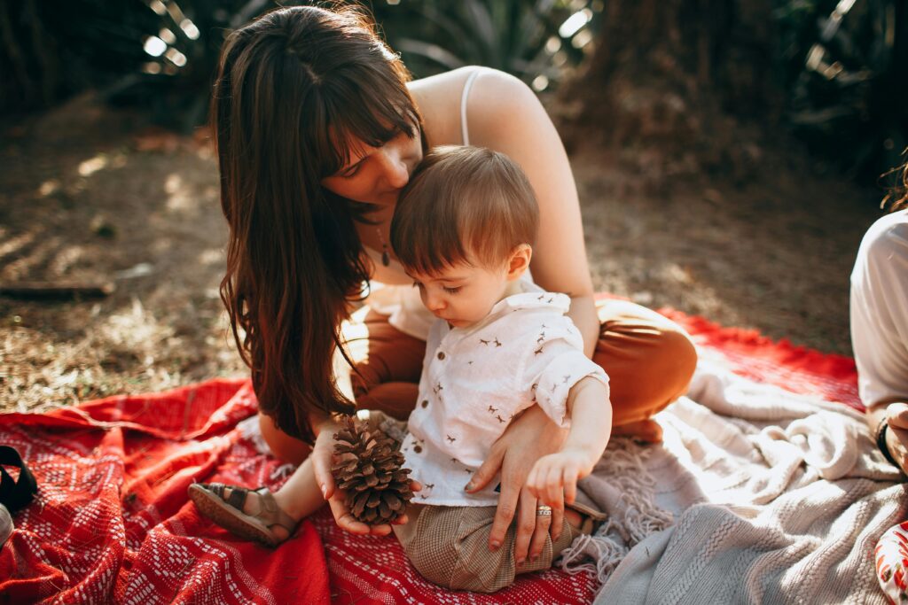 A woman and a baby are sitting on a blanket