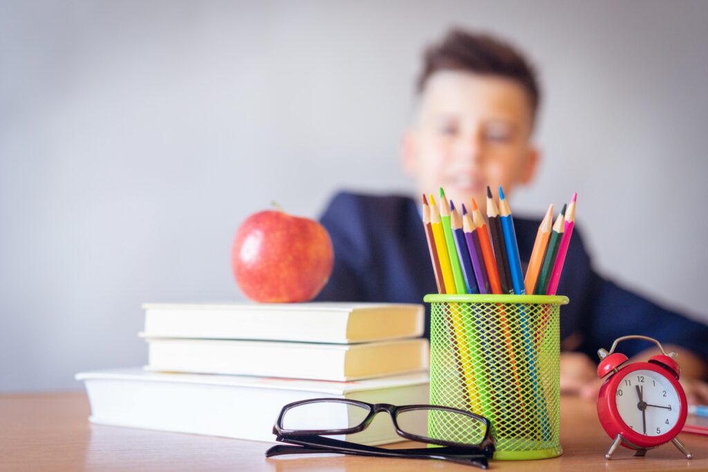 Child sitting at desk, with apple and school supplies