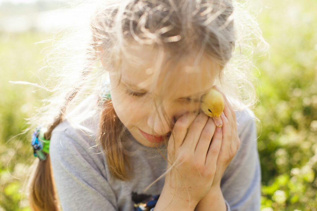 Child in gray long sleeve shirt holding yellow duck