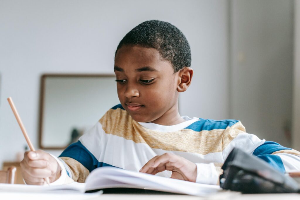 Positive boy doing homework in copybook