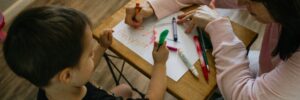 boy in white long sleeve shirt writing on white paper