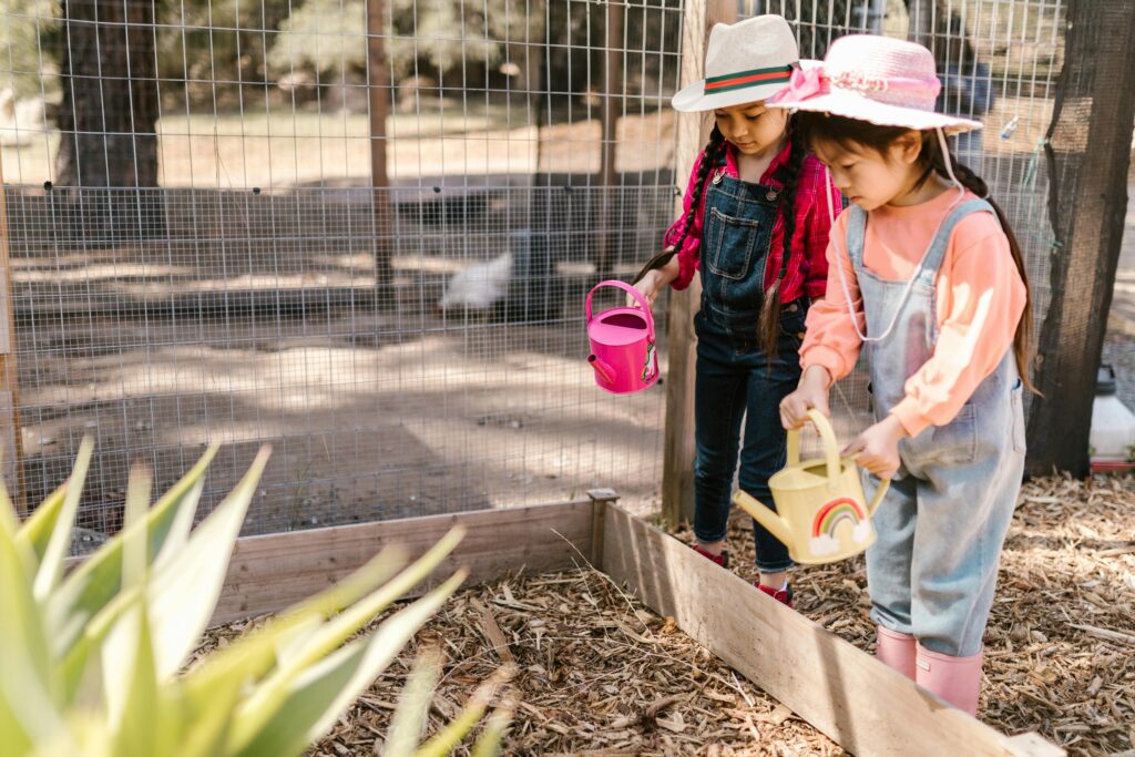 Two Young Girls Using Watering Cans for Gardening