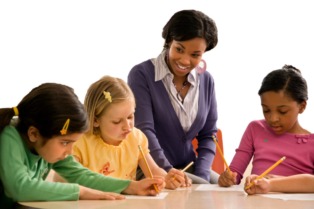 Children learning at a desk with teacher