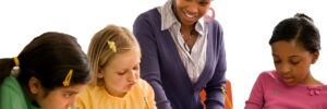 Children learning at a desk with teacher