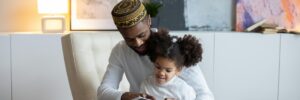 Smiling black father reading book to adorable daughter
