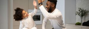 Joyful father giving high five to adorable daughter