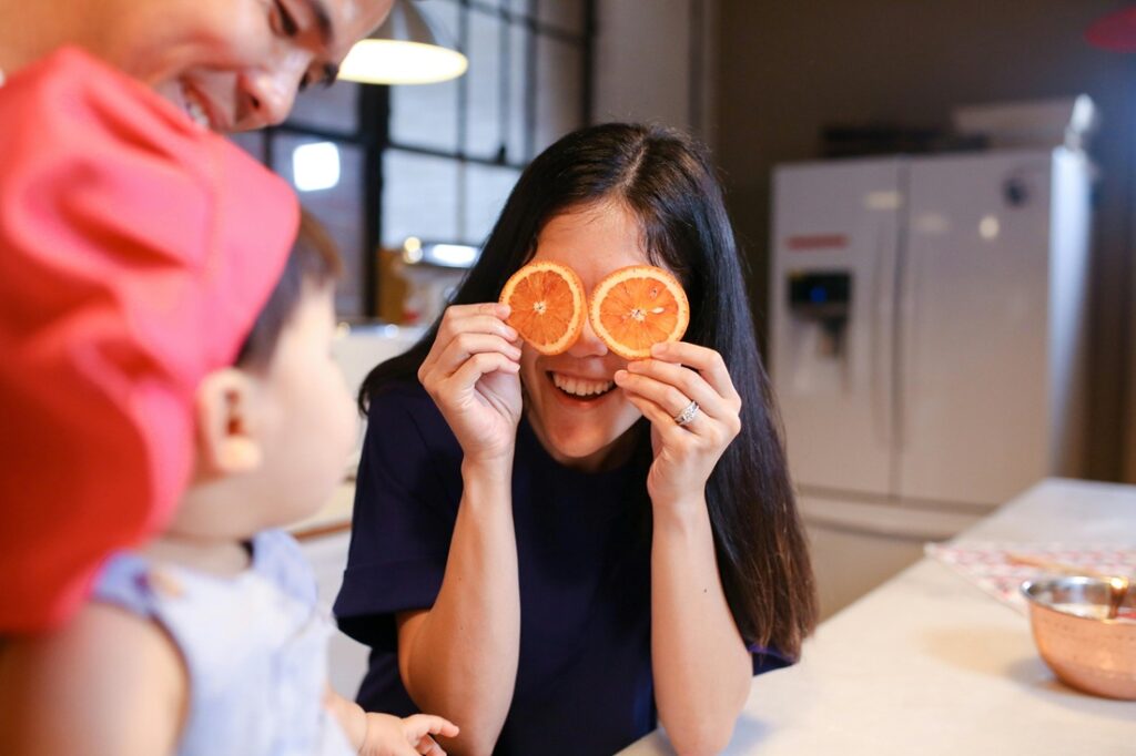 A Happy Woman Covering her Eyes with Orange Slices