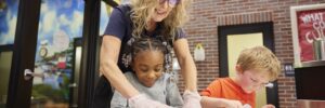 Teacher helping a student make cookies.