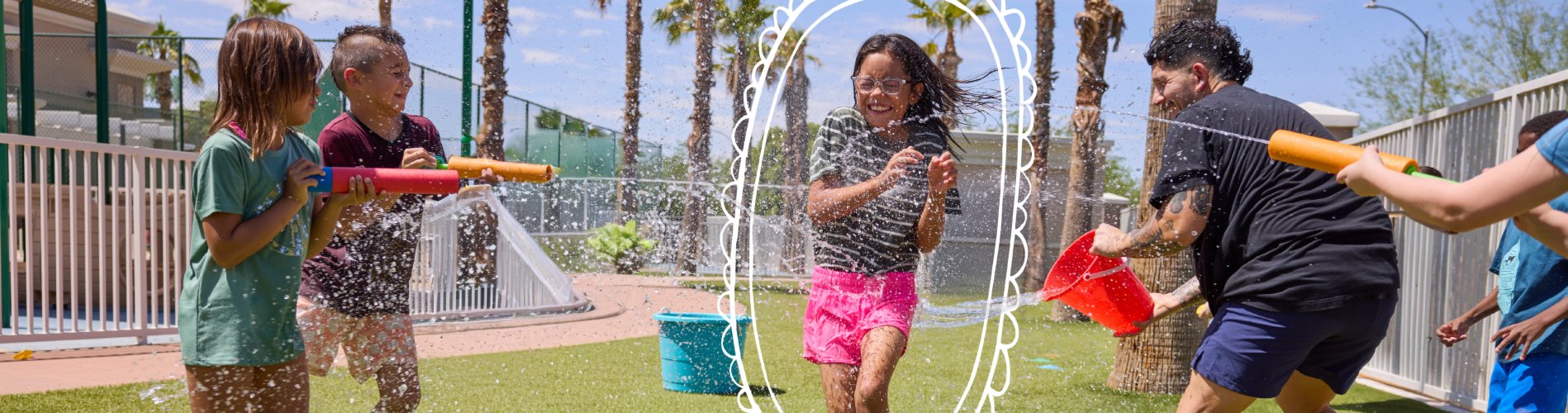 A young girl in a grey shirt kicking a soccer ball on a field during an outdoor summer camp game with other kids.