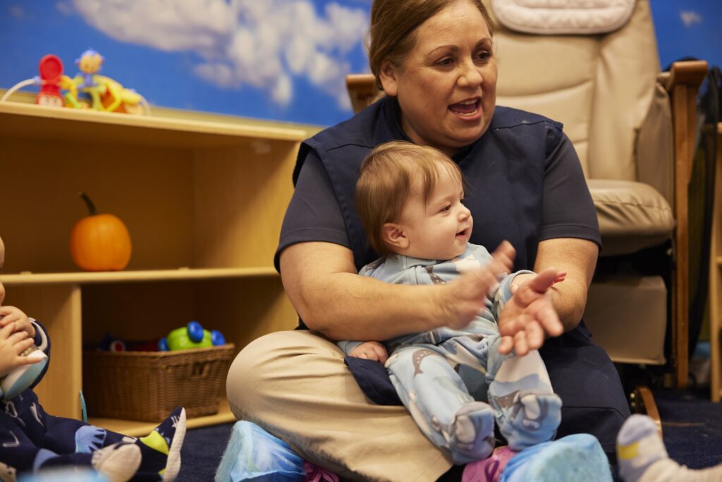 Toddler in lap and Teacher clapping