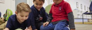 3 children reading a book on the floor