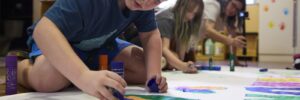 Child drawing on a large mural on the ground