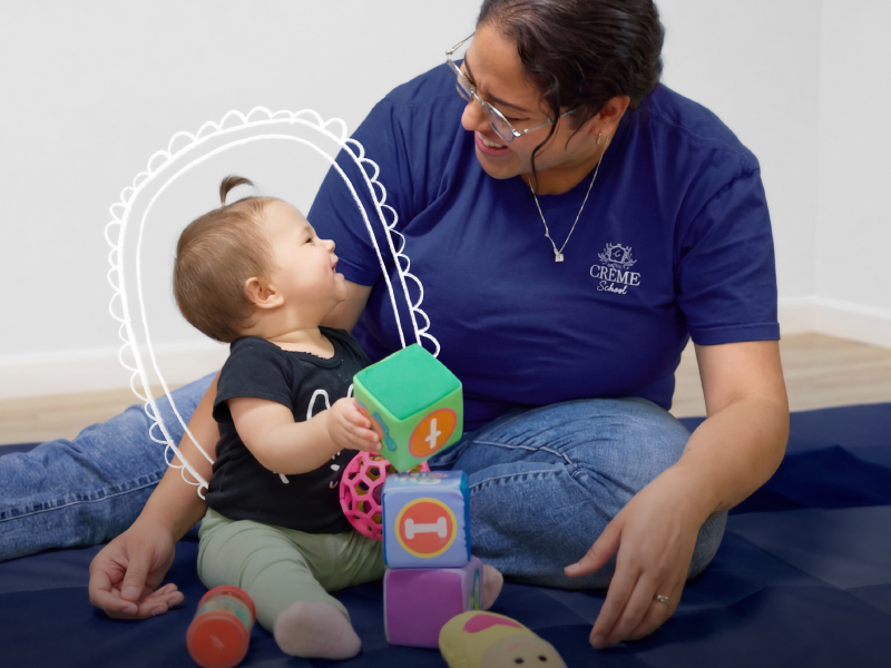 Two caregivers, holding and looking after infants at Crème School infant daycare.
