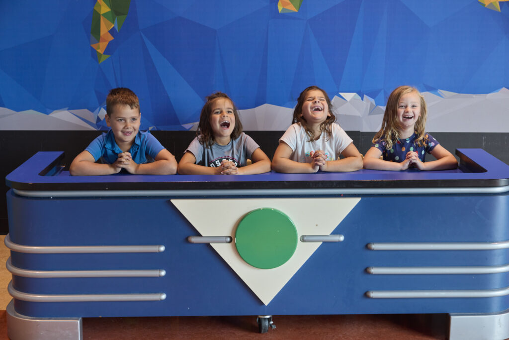 Children sitting at a game show table laughing