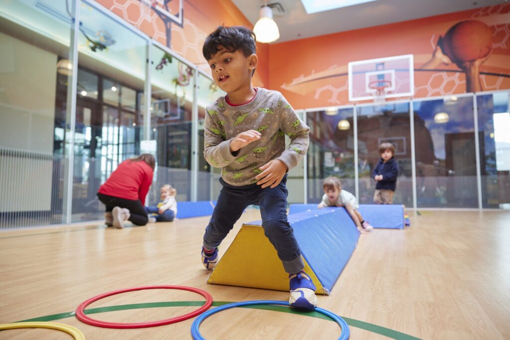 Child playing in a gym with other children playing in the background