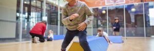 Child playing in a gym with other children playing in the background