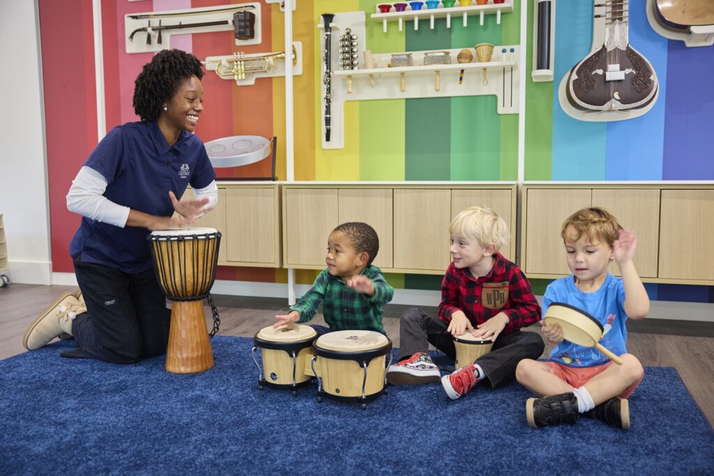 Children and a teacher sitting on the floor playing instruments
