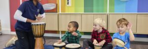 Children and a teacher sitting on the floor playing instruments