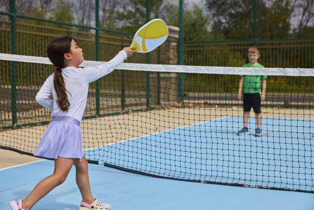 Two children playing pickleball