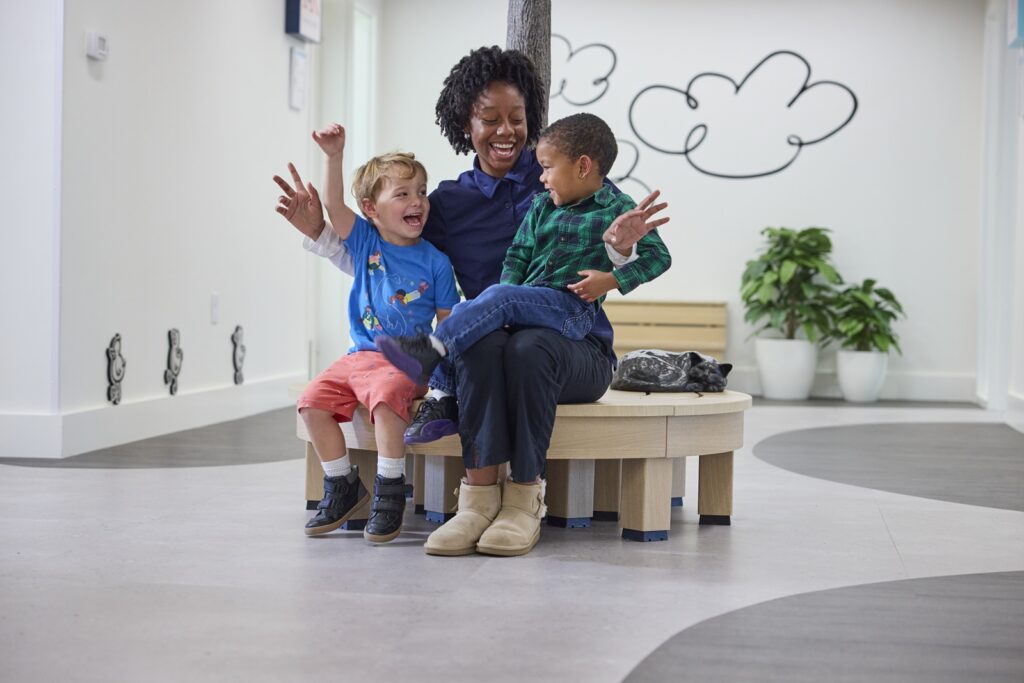 Teacher and two students happy and smiling in preschool lobby